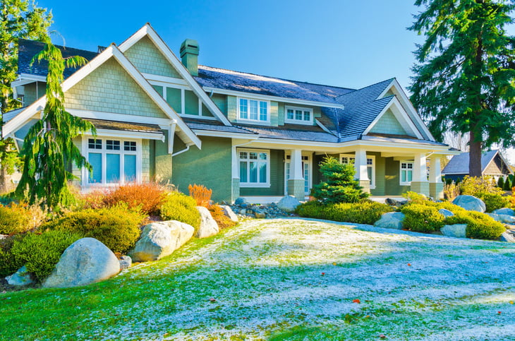 Home with outdoor landscape and lawn covered with snow patches on a winter day in suburbs of Vancouver, Canada