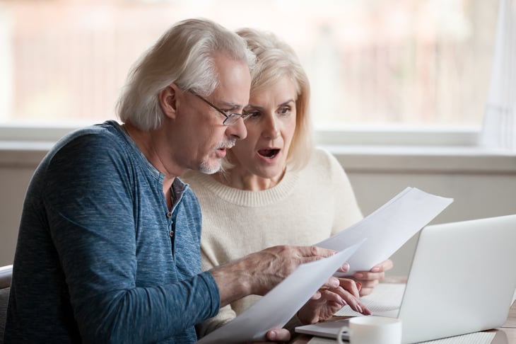 senior man woman worried computer papers