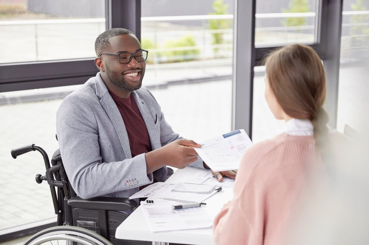Smiling man in a wheelchair working and in a meeting or interview