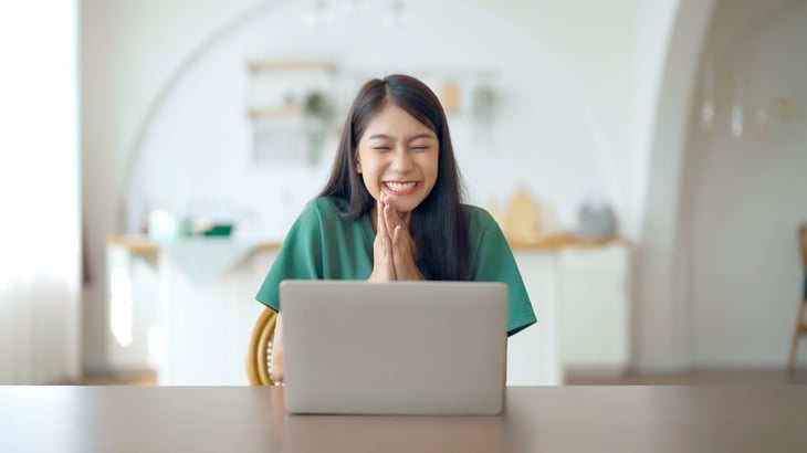 Happy and excited young woman sitting at her laptop
