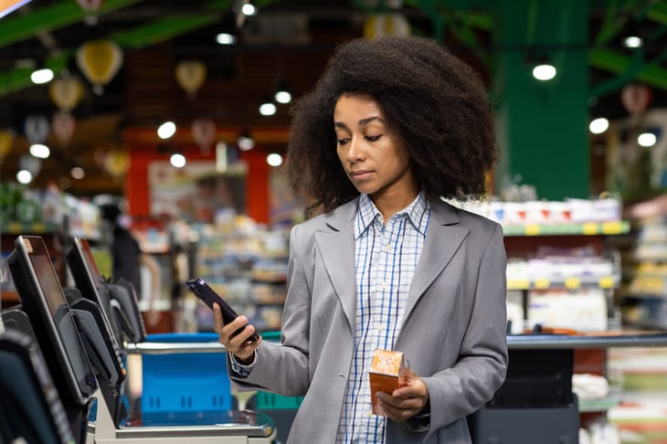 Woman using a buy now pay later option on her smartphone to pay for groceries